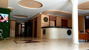 A reception area with a reception desk, a television mounted on the wall, and a reception sign. - Clepsydra Residence (Plovdiv)