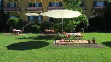 An outdoor seating area with tables and chairs, umbrellas, and a building in the background.