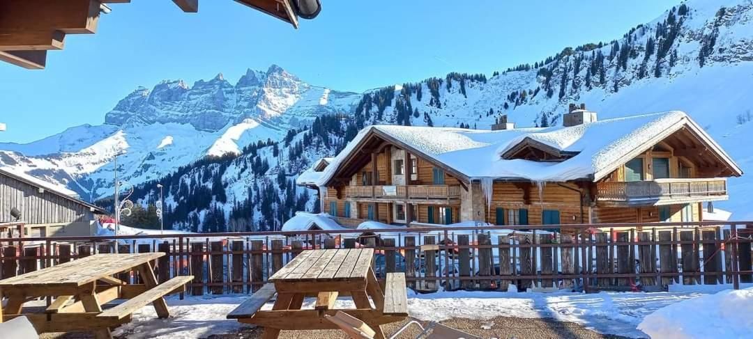 Un chalet de madera con balcón, rodeado de montañas nevadas.