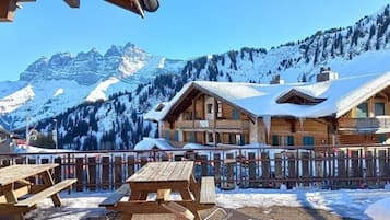 A wooden chalet with a balcony, surrounded by snow-covered mountains.
