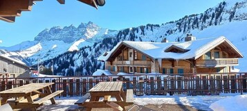 Un chalet de madera con balcón, rodeado de montañas nevadas.