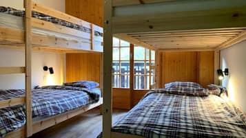 A bunk bed room with wooden walls and a window.