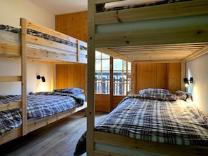 Habitación con literas, paredes de madera y una ventana.