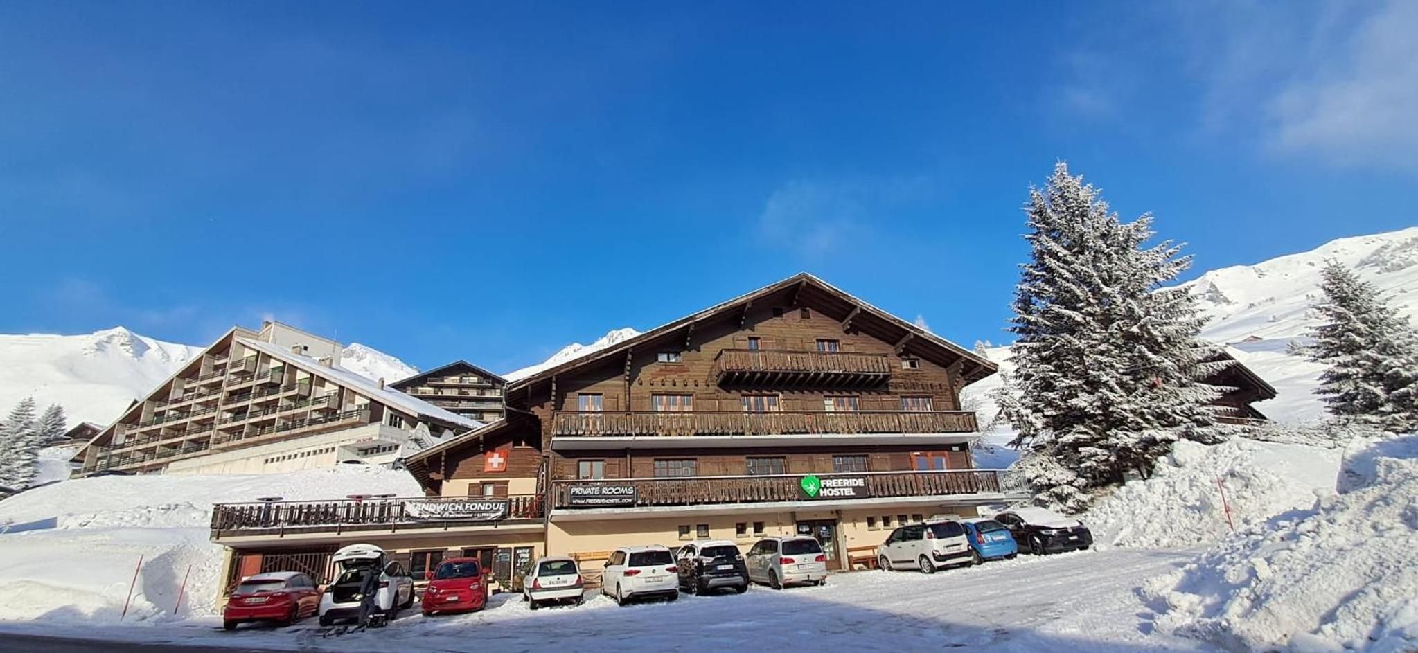 A multi-story hotel with balconies, private rooms, and a ski resort backdrop.