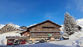 A multi-story hotel with balconies, private rooms, and a ski resort backdrop.