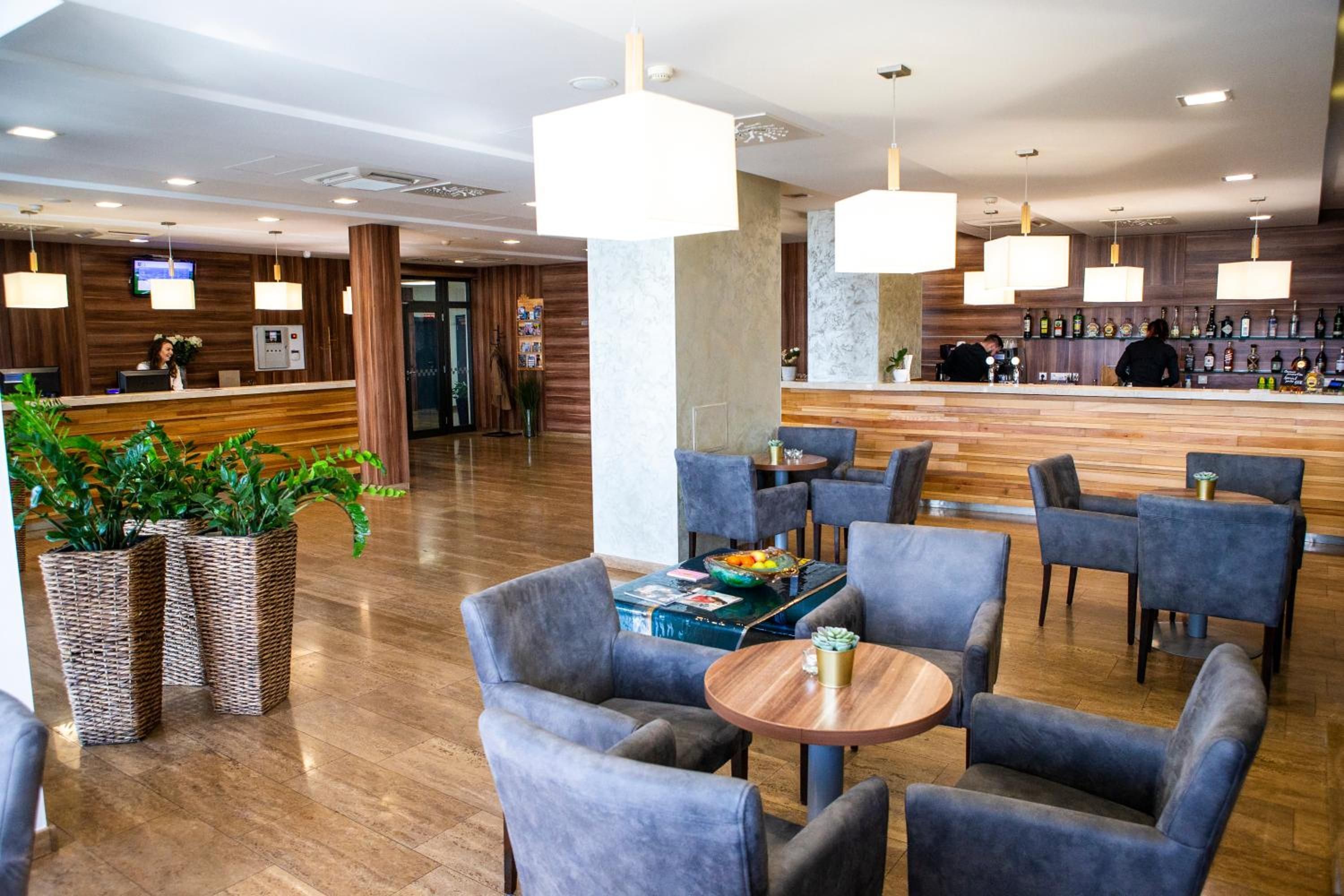 A hotel lobby with a reception desk, seating area, and a bar.