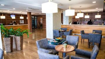 A hotel lobby with a reception desk, seating area, and a bar.