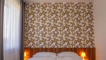 A hotel room with a wooden bed frame, a patterned wall, and two bedside lamps.