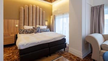 A modern hotel room with a large bed, a seating area, and a ceiling mural.