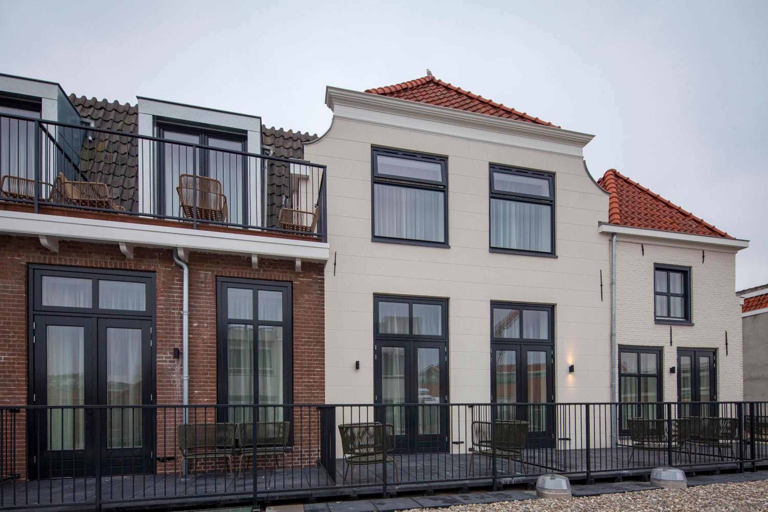 A row of residential buildings with balconies, brick facades, and large windows.