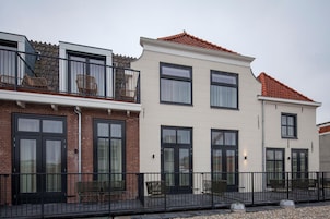 Una hilera de edificios residenciales con balcones, fachadas de ladrillo y grandes ventanales.