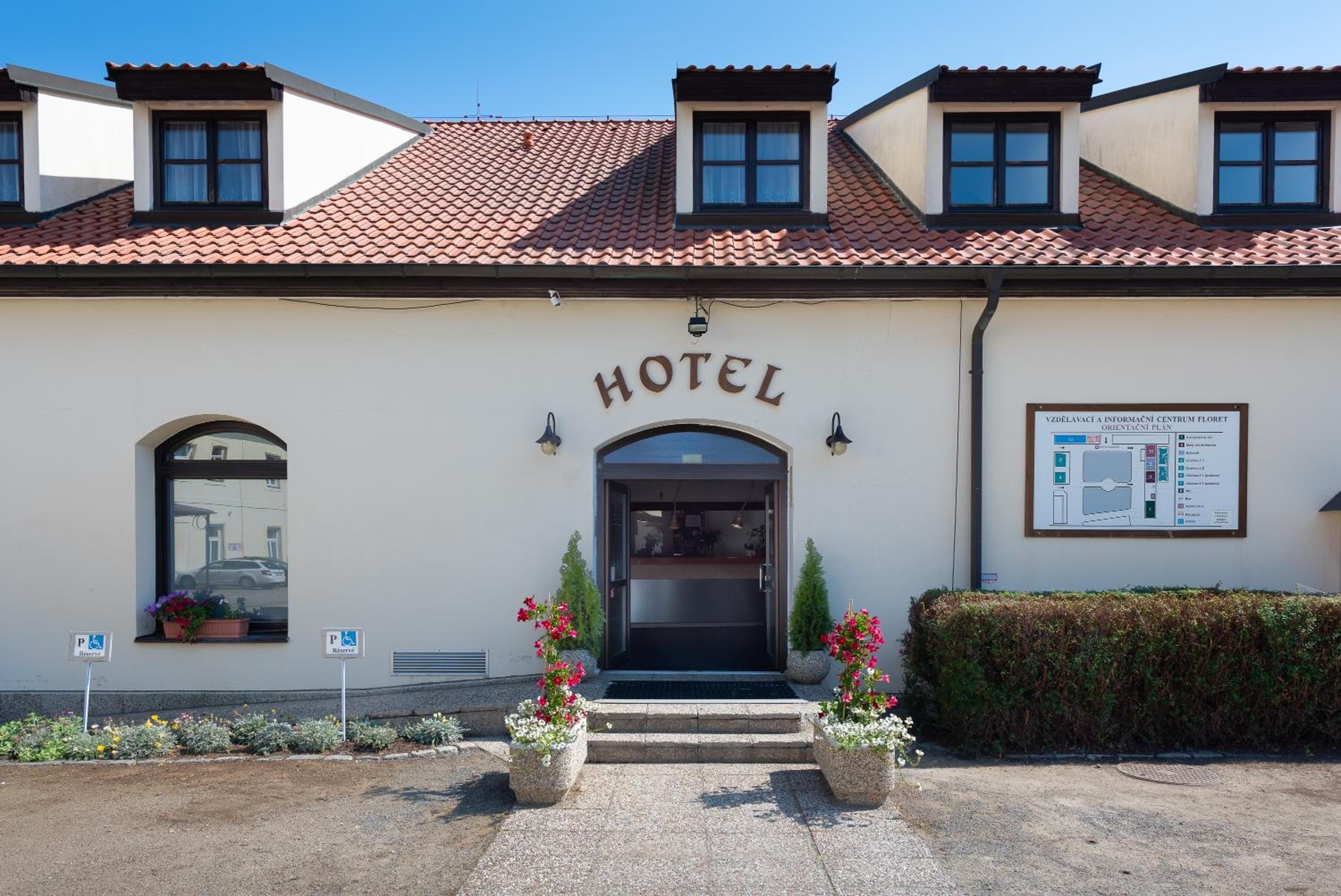 A hotel with a tiled roof, a central entrance, and a signboard.