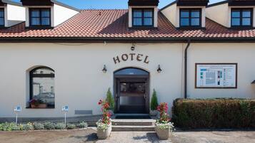 Ein Hotel mit einem Ziegeldach, einem zentralen Eingang und einem Schild.