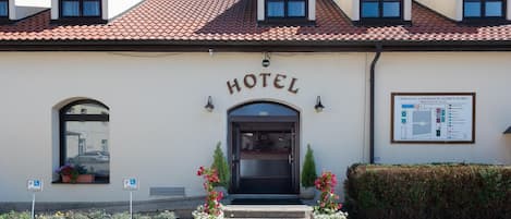 A hotel with a tiled roof, a central entrance, and a signboard.