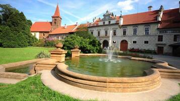 Ein Innenhof mit einem Brunnen, umgeben von einer Steinmauer und Pflanzen.