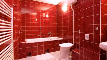 Ein Badezimmer mit roten Fliesen, einer weißen Badewanne, einer weißen Toilette und einem weißen Waschbecken.
