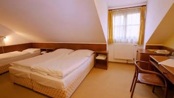 Ein Hotelzimmer mit zwei Betten, einem Schreibtisch, einem Stuhl und einem Fenster mit Vorhängen.