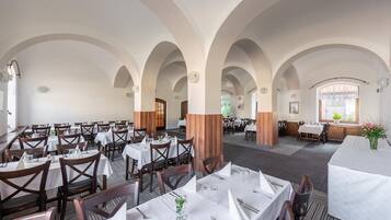 Ein Restaurant mit mehreren Tischen, Holzkästen und weißen Tischdecken.