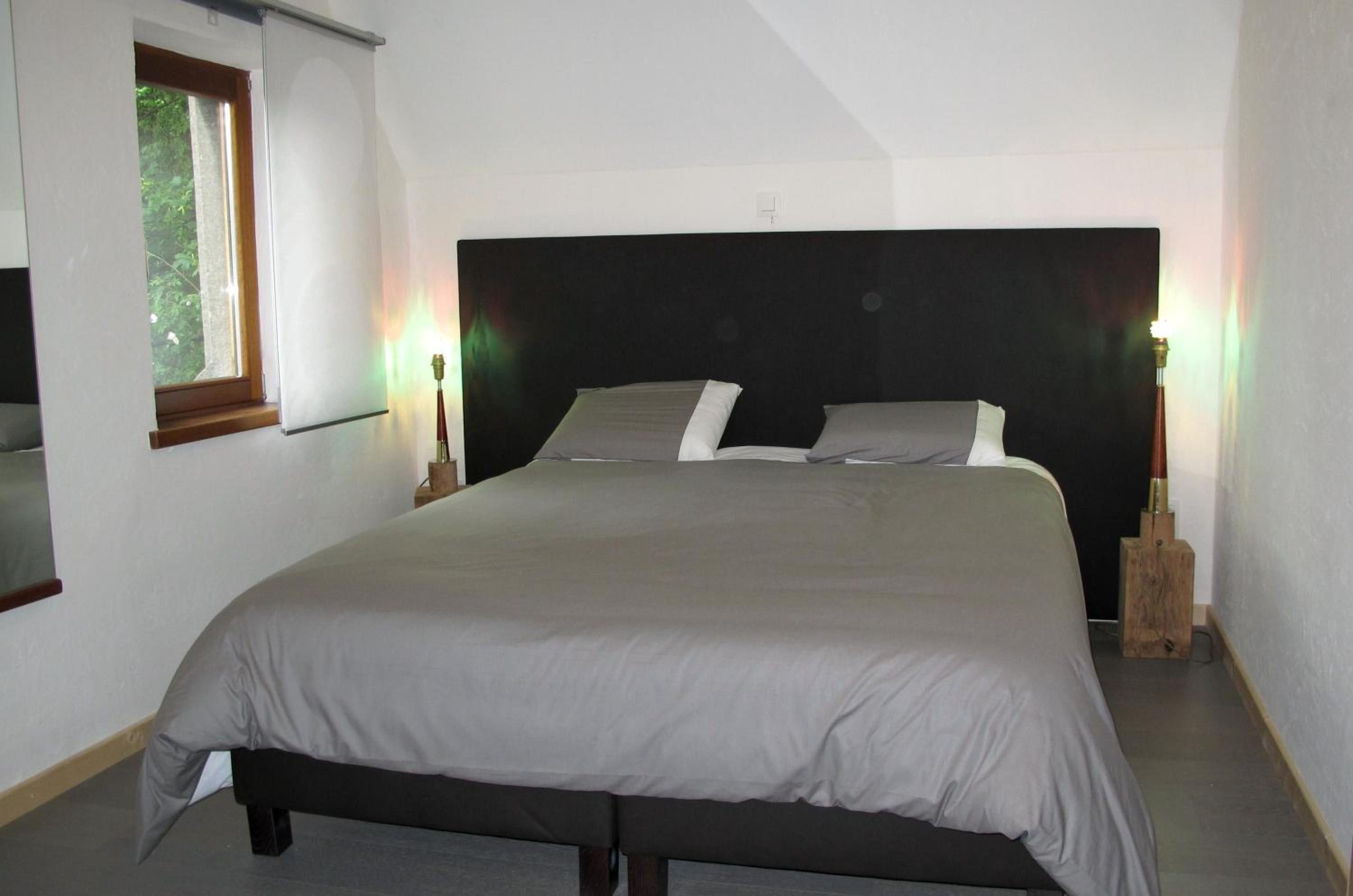 A bedroom with a large bed, a window, and two bedside lamps.