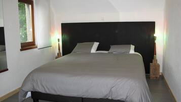 A bedroom with a large bed, a window, and two bedside lamps.