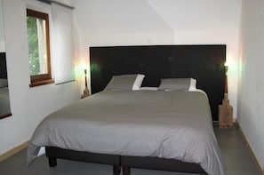 A bedroom with a large bed, a window, and two bedside lamps. - Stone Station (Esneux)