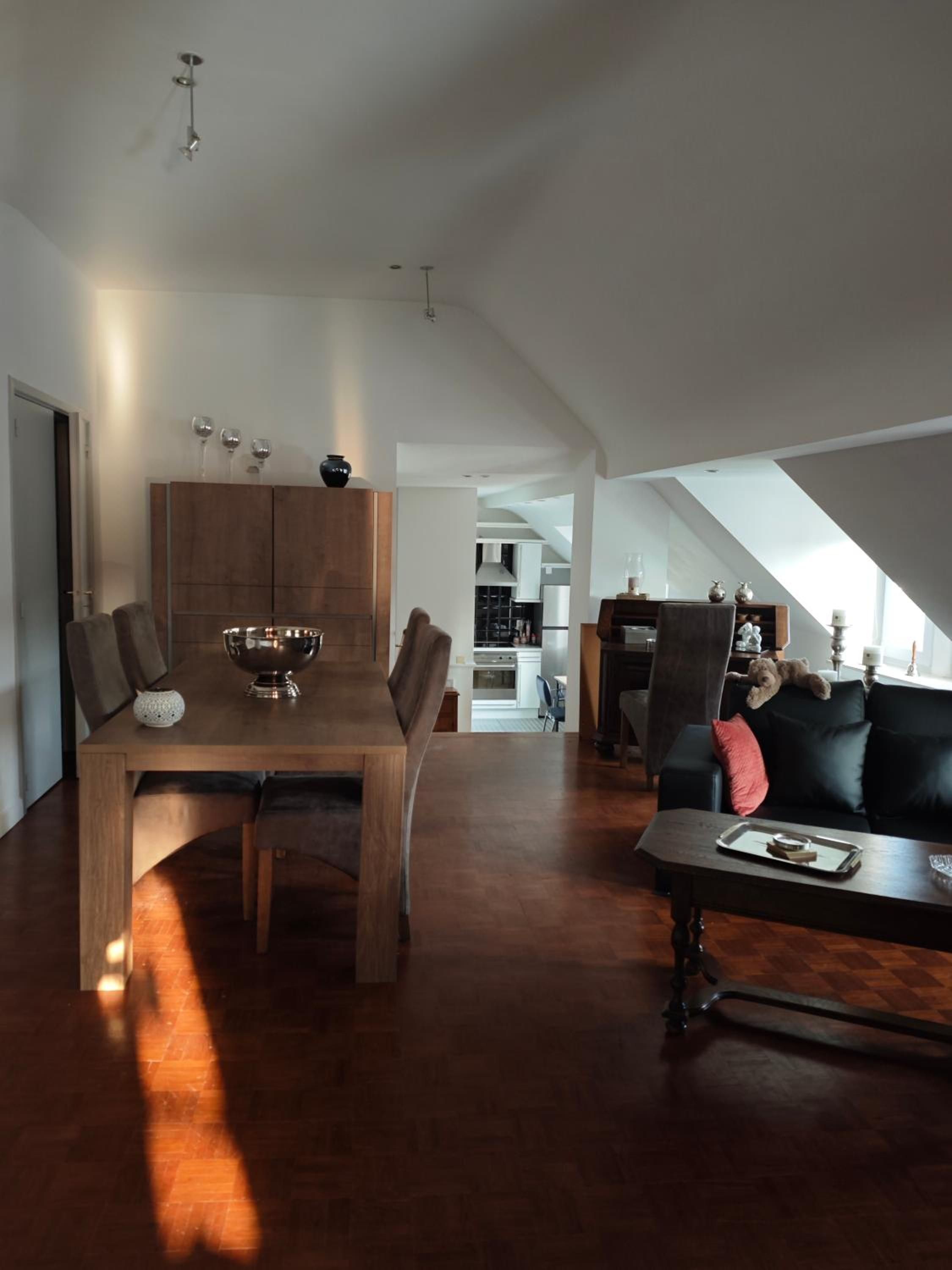 A spacious living area with a dining table, a sofa, and a kitchen in the background.