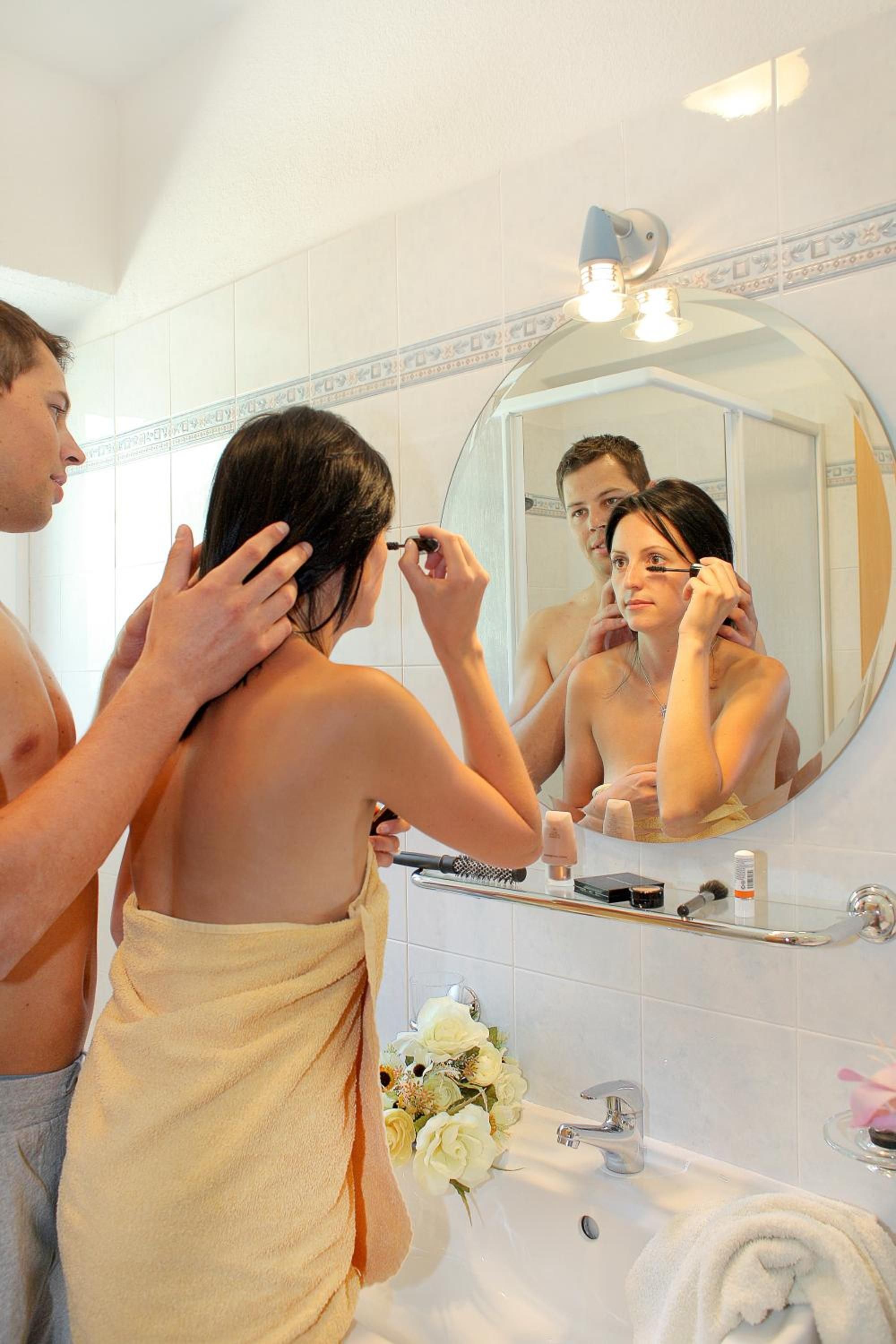 A bathroom with a large mirror, a sink, and a towel rack.