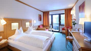 Quarto de hotel com duas camas, uma escrivaninha com computador, uma cadeira e vista para o exterior.