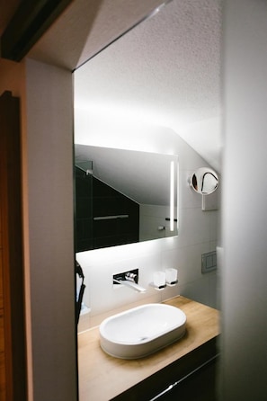 A modern bathroom with a white sink, a mirror, and a towel rack. - Hotel Restaurant Zum Schwarzen Bv Ren (Andermatt)