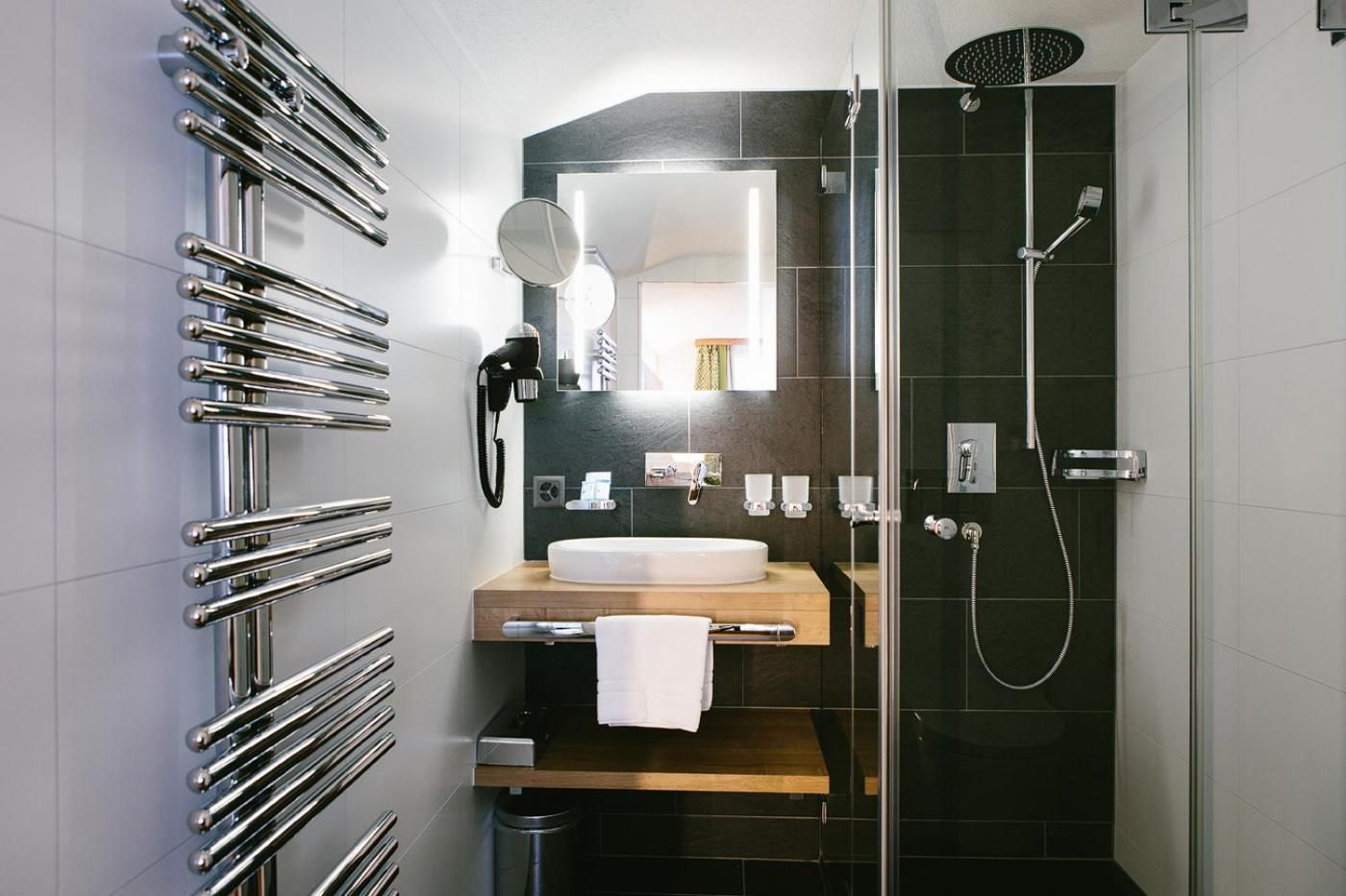 Un baño moderno con cabina de ducha de vidrio, lavamanos integrado y toallero.