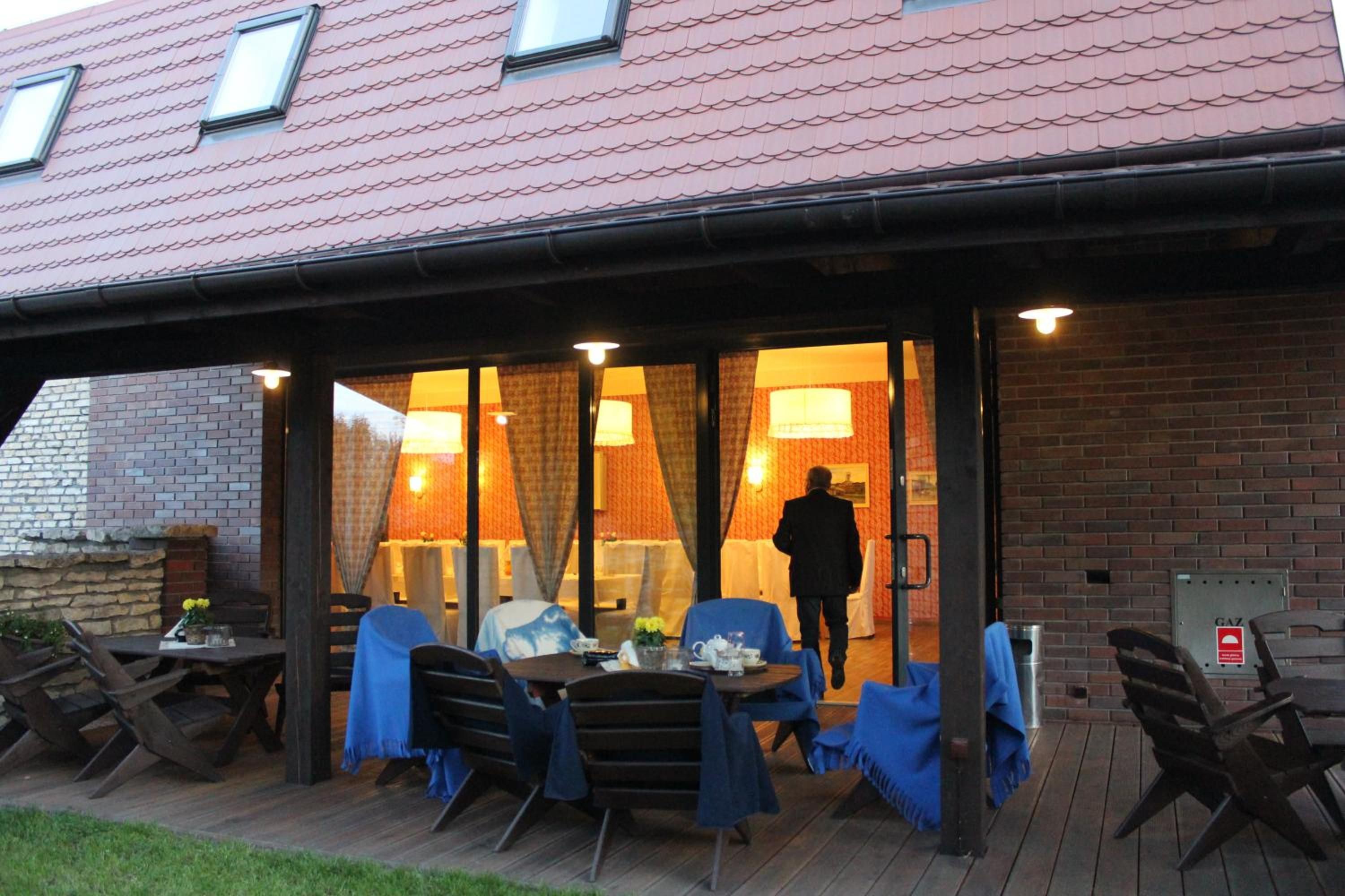 An outdoor seating area with tables and chairs, a covered entrance, and a brick wall.