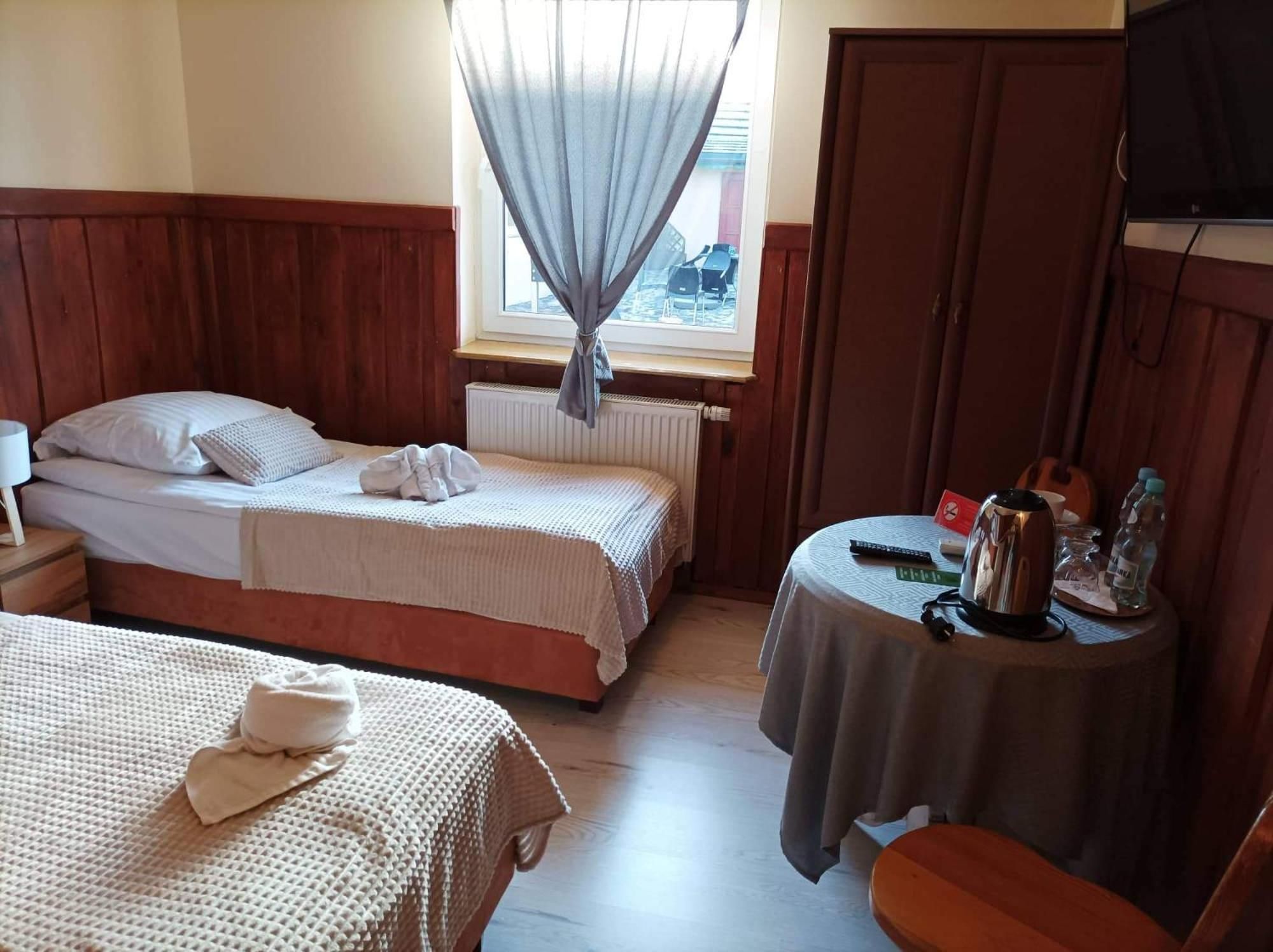 Ein Zimmer mit zwei Betten, einem Tisch mit Wasserkocher und einem Fernseher.
