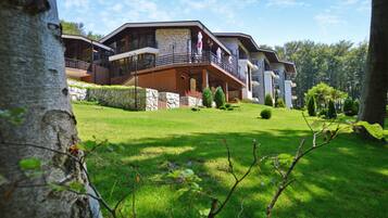 A multi-story building with balconies, a stone facade, and a well-maintained lawn.