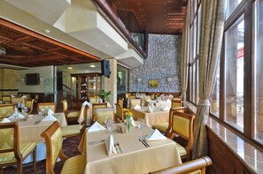 Um restaurante com várias mesas, cadeiras e uma parede de pedra.
