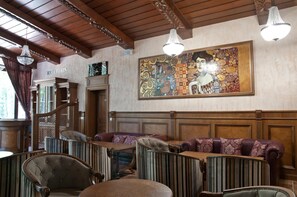 A reception area with a large, colorful abstract painting, wooden paneling, and a chandelier. - Hotel Edelweiss (Kazanlak)