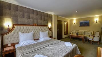 A hotel room with a large bed, a sofa, a desk, and a mirror.