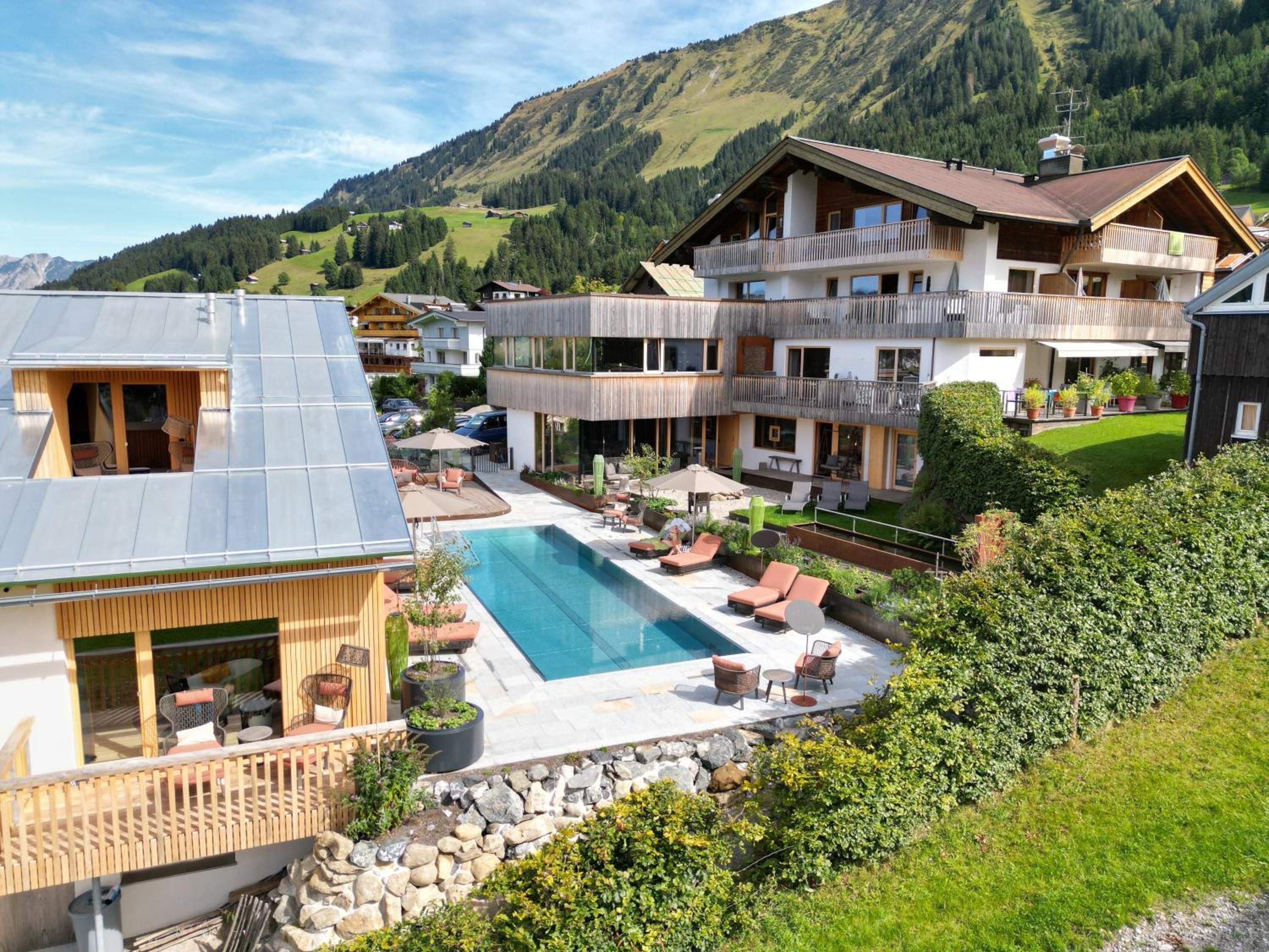 Ein Wohngebiet mit Schwimmbad, Sitzgelegenheiten im Freien und Blick auf Berge.