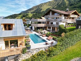 A residential area with a swimming pool, outdoor seating, and a view of mountains.