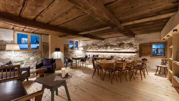 Ein rustikales Interieur mit einer Steinwand, Holzmöbeln und einer hohen Decke.
