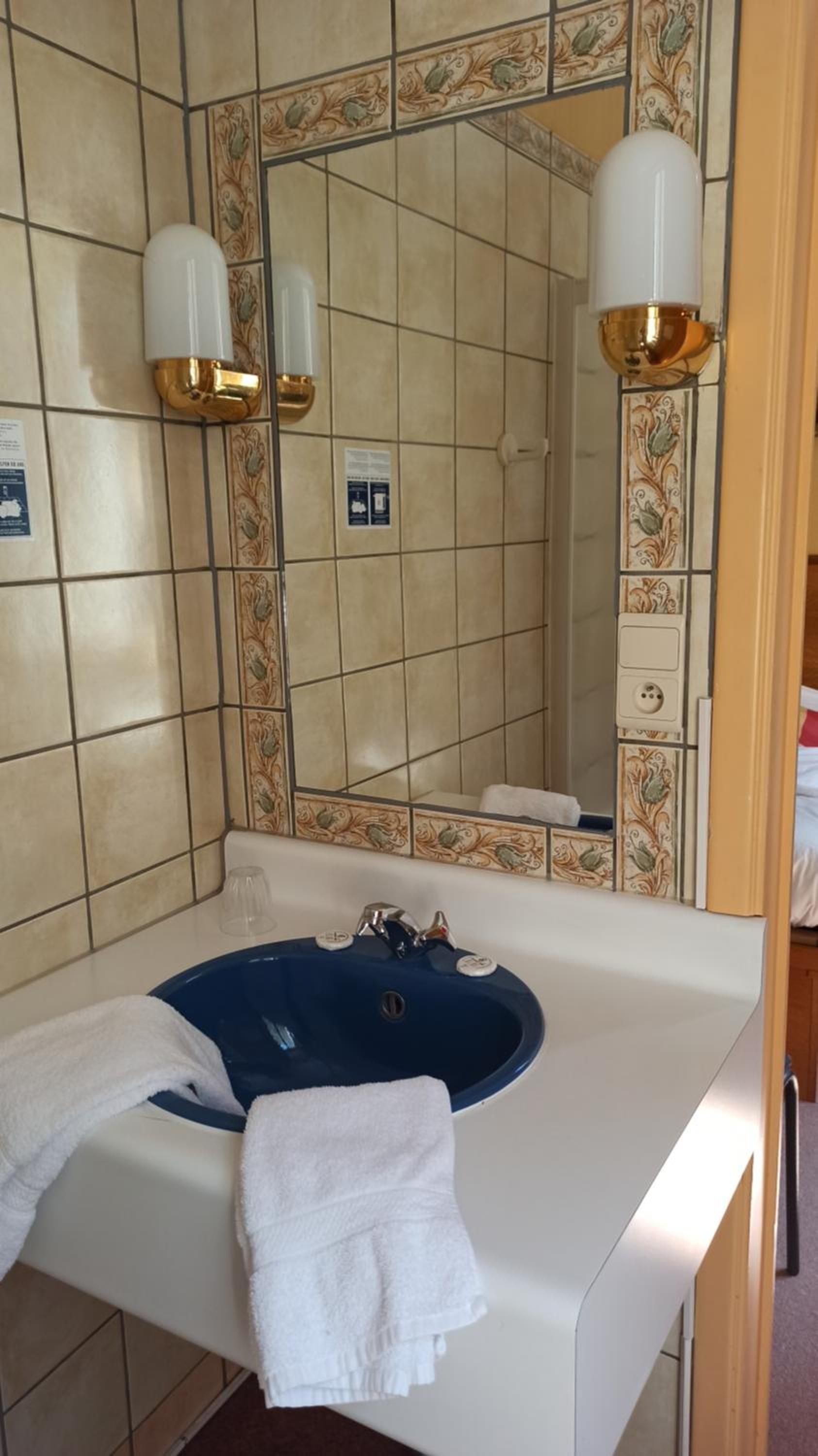 Een badkamer met een wit wastafelmeubel, een blauwe wasbak en twee wandlampen.