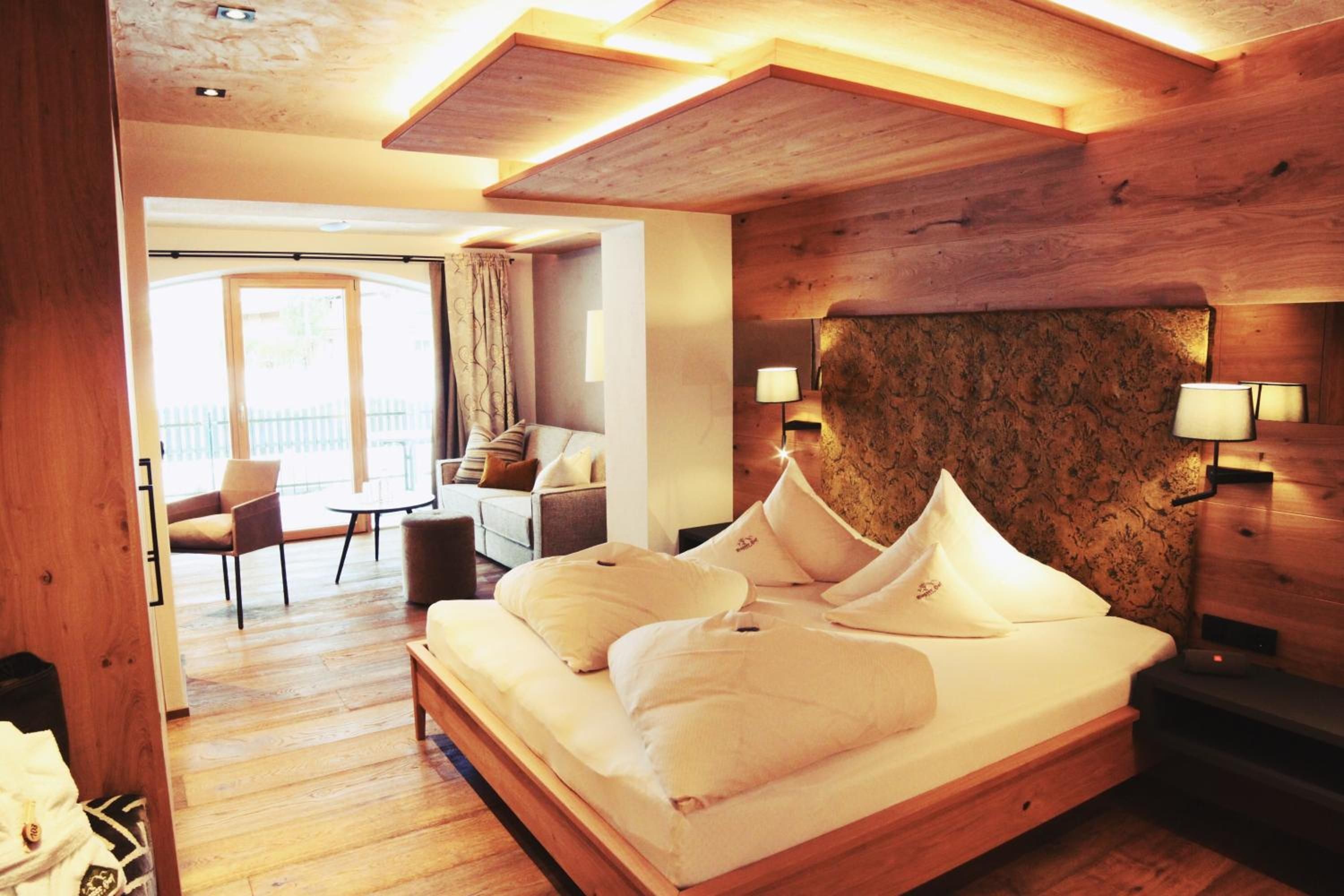 Ein Hotelzimmer mit einem hölzernen Kopfstück, einem Bett mit weißer Bettwäsche, einem Schreibtisch und einem Stuhl.
