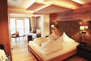 Una habitación de hotel con cabecera de madera, una cama con ropa blanca, un escritorio y una silla.