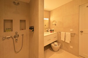 Un baño con ducha, lavamanos, espejo y toallero.