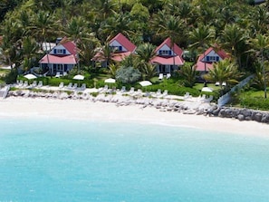 Propiedad frente al mar con varias casas, una playa de arena y palmeras.