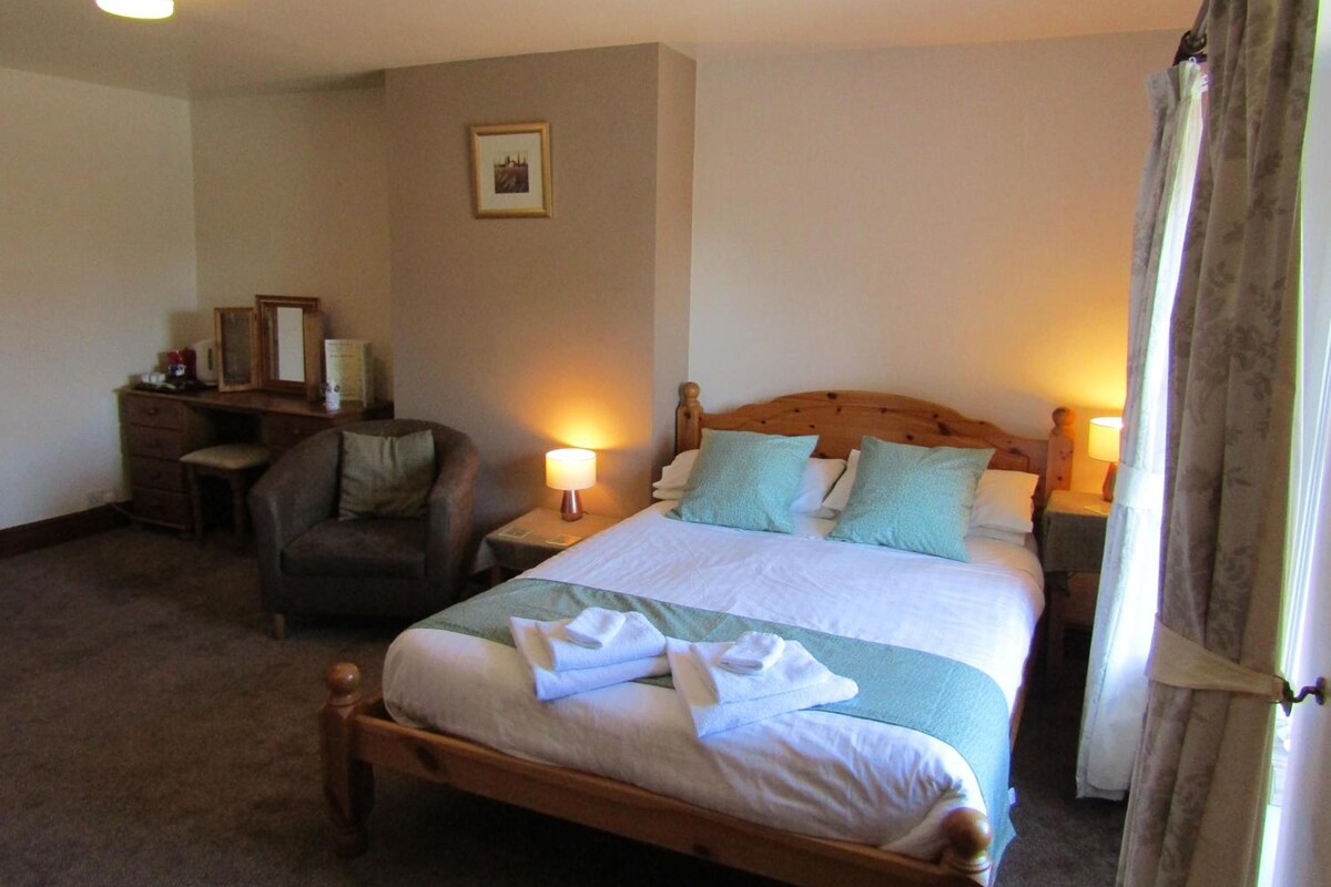 Une chambre d’hôtel avec un lit, un bureau, une chaise et un tableau au mur.