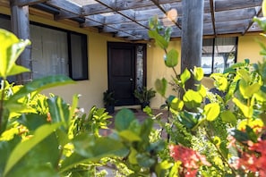 A covered porch with a wooden ceiling, a black door, and potted plants.