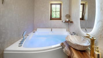 A modern bathroom with a freestanding bathtub, a wooden vanity, and a small window.