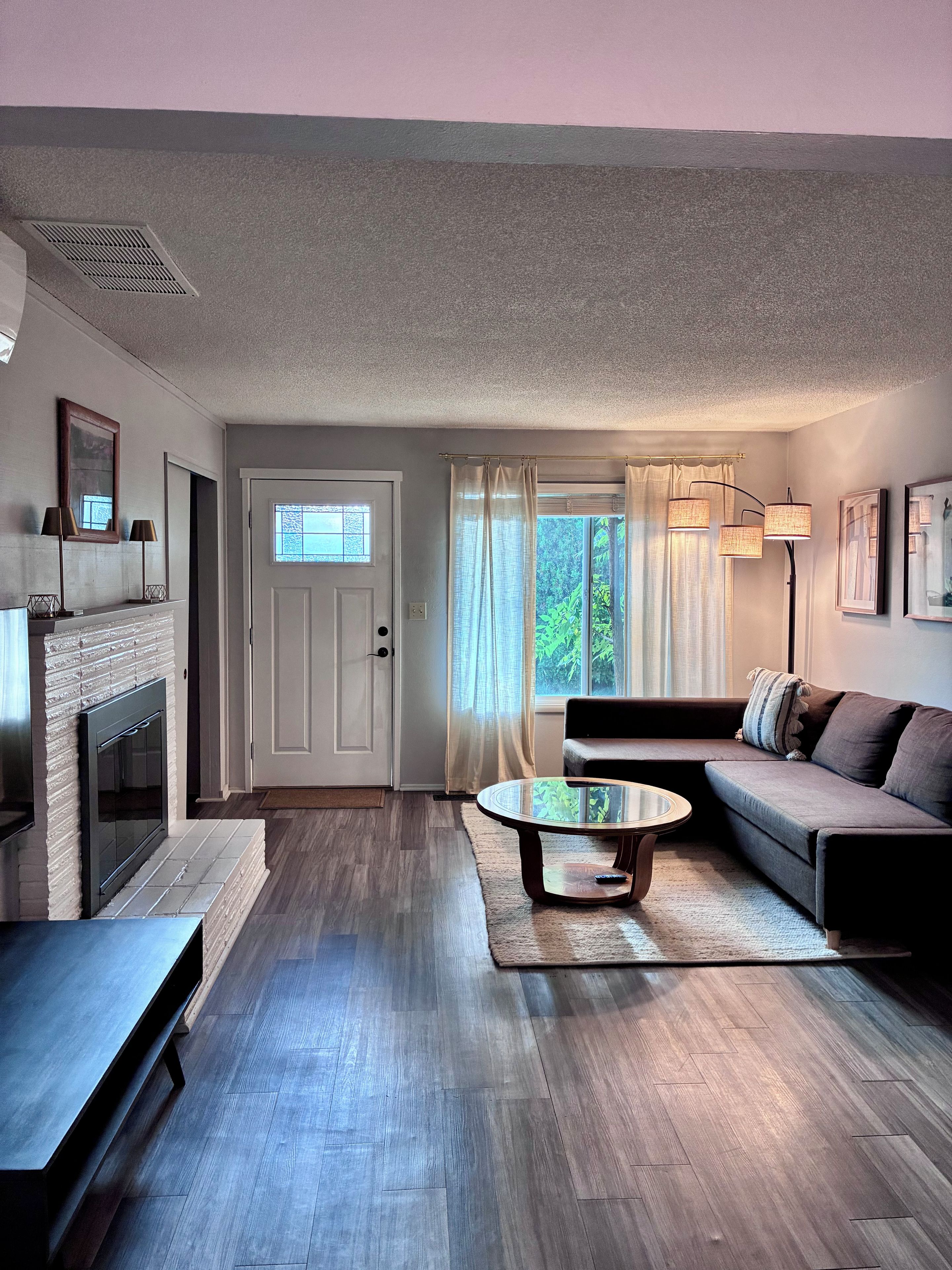 A modern living room with a fireplace, a sofa, a coffee table, and a lamp.