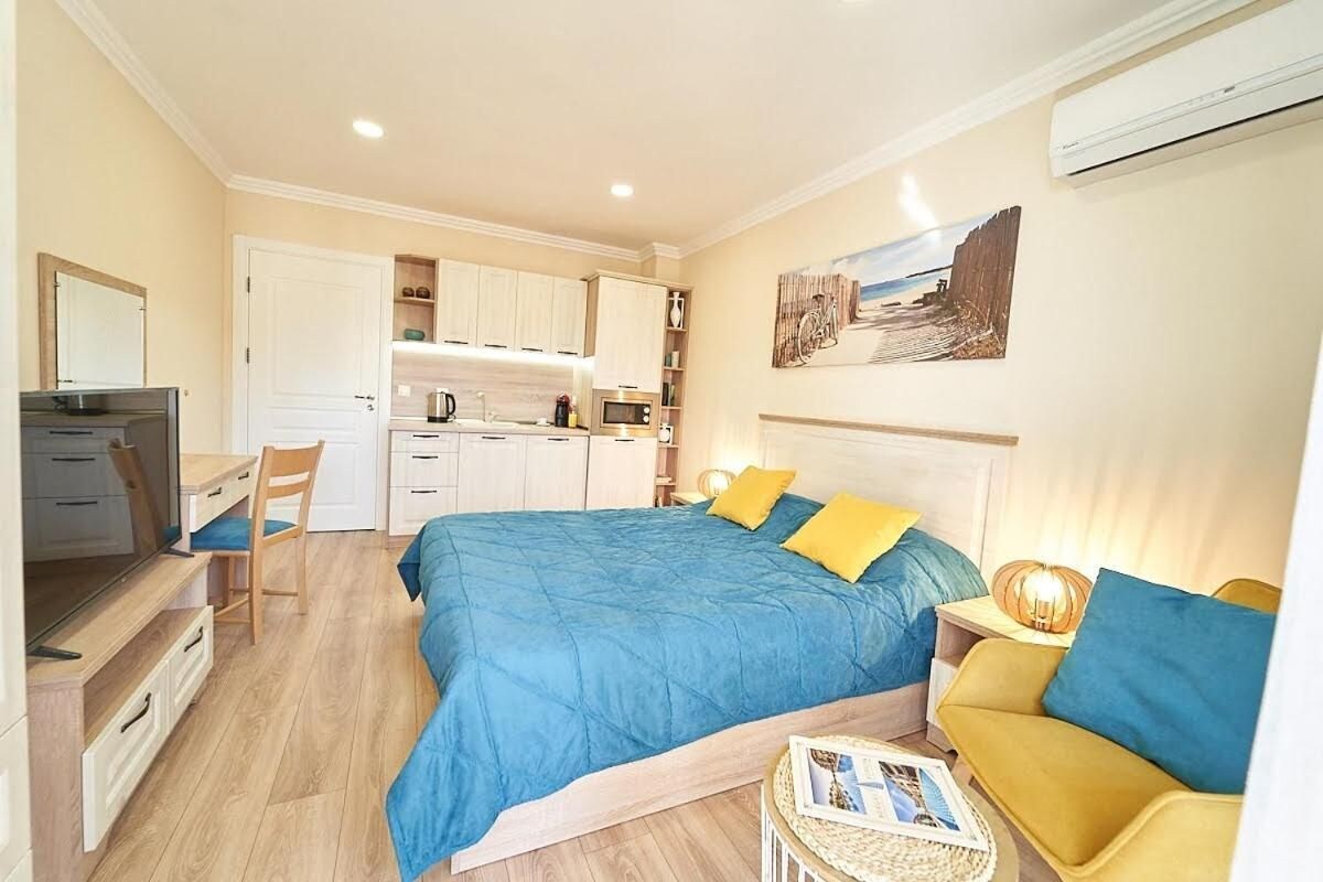 A compact bedroom with a bed, bedside table, and a small seating area.