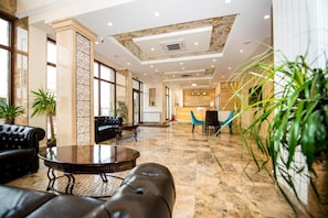 A hotel reception area with a reception desk, seating arrangements, and a large window providing natural light. - Burgas Beach Resort Apartments (Burgas)